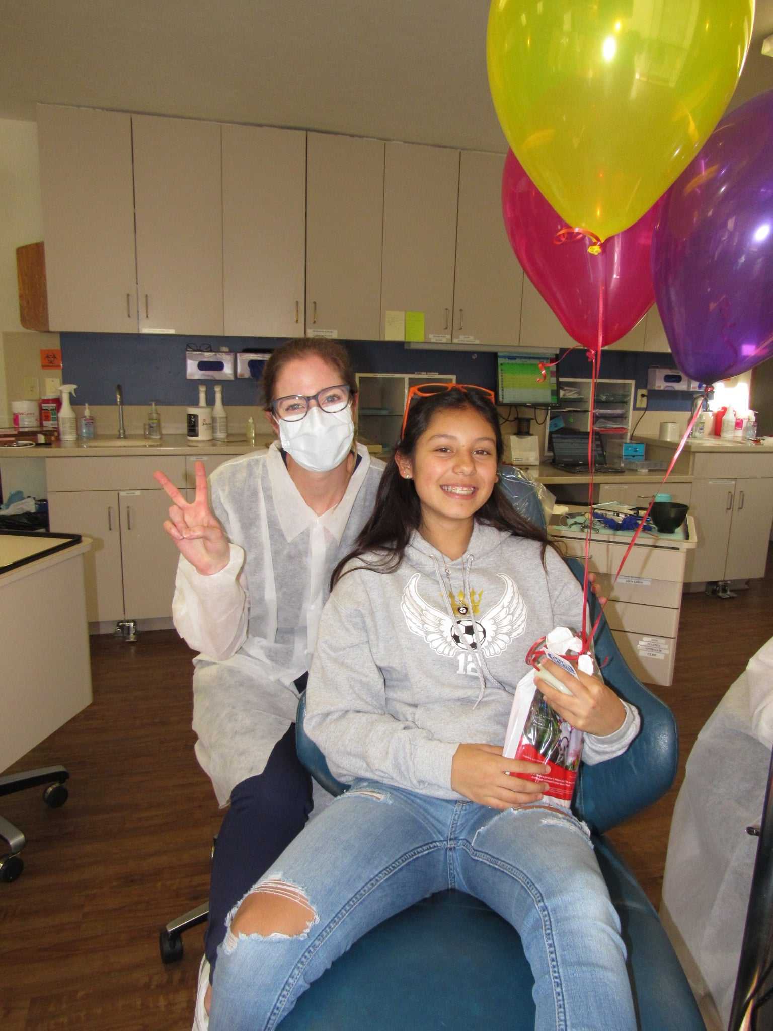 Team member posing with a patient with balloons