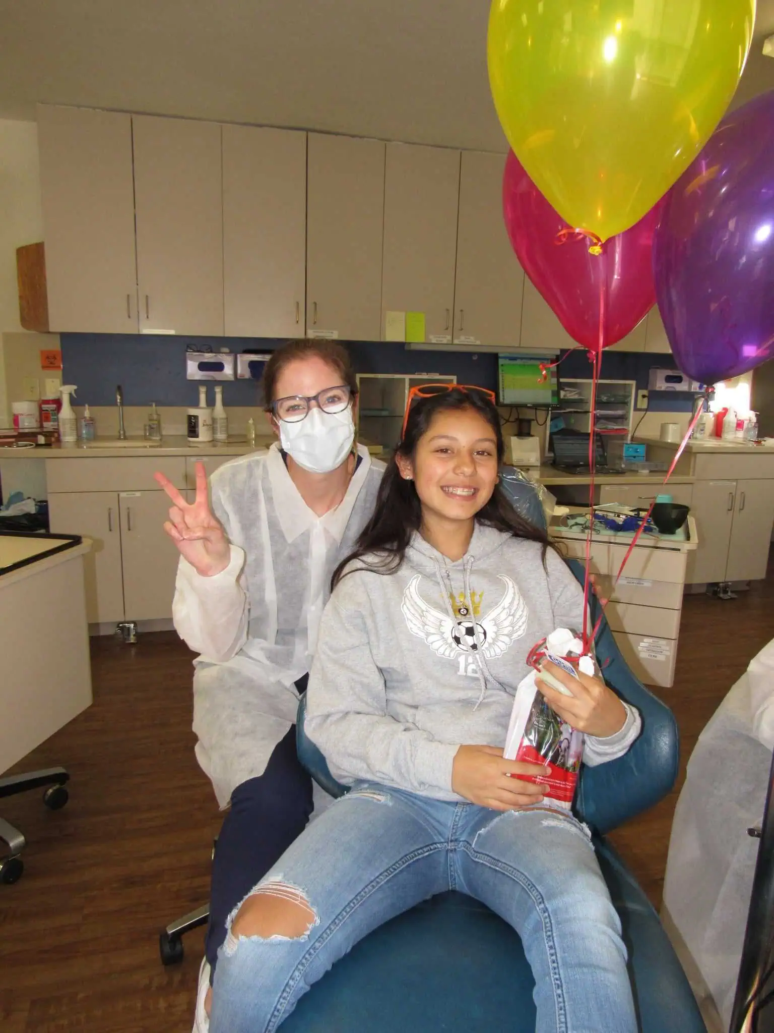 Smiling patient and orthodontist with braces and balloons in Monterey Bay Orthodontics office.
