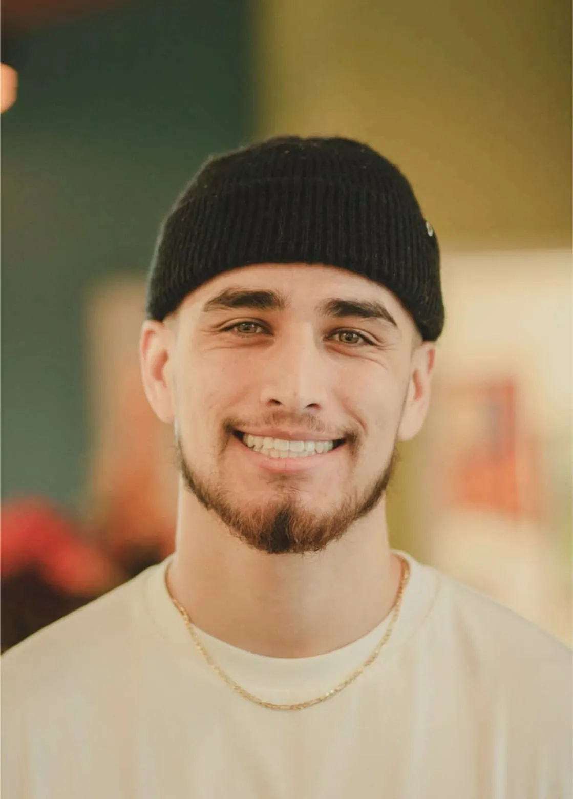 Smiling young man wearing a black beanie and white shirt, showcasing a confident smile, representing the orthodontic services at Monterey Bay Orthodontics.